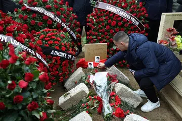 Seorang lelaki meletakkan gambar mangsa nahas pesawat, Mahammadali Eganov, 13 tahun, di kuburnya di Baku, Azerbaijan, pada 28 Disember.