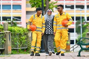 Encik Muhammad Aufa Aniq Mohamed Salizaldan (kiri) dan abangnya, Muhammad Nurshadiqqin Mohamed Salizal (kanan), sentiasa saling menyokong ketika bertugas sebagai pakar pengikat kontena di sebuah syarikat pengurusan kontena dan logistik, Call Lade Enterprises. Bersama mereka ialah Ibu mereka, Cik Siti Sufiyyah Ithnin, yang mulanya bimbang akan keselamatan kedua-dua anaknya itu tetapi lega dengan latihan yang disediakan.