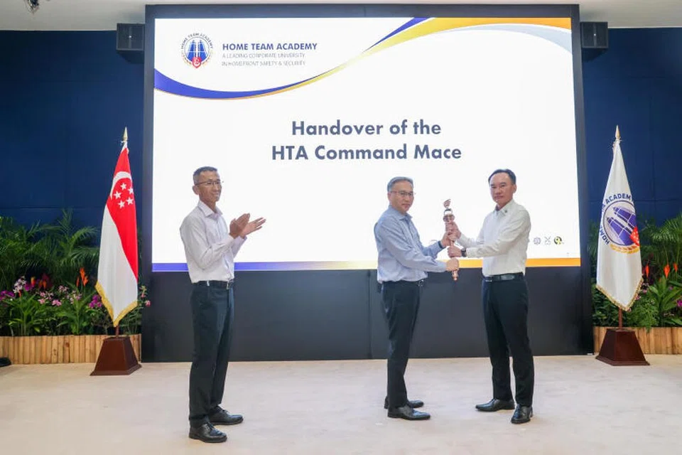 Setiausaha Tetap Kementerian Ehwal Dalam Negeri (MHA), Encik Pang Kin Keong (tengah), menghulurkan cokmar kepada Ketua Eksekutif (CE) Akademi Home Team (HTA), Encik Wilson Lim (kanan), yang akan menggantikan Encik Anwar Abdullah secara rasmi pada 11 Januari.