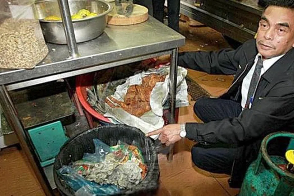 KOTOR DAN MELOYAKAN: Encik Ahmad Shukri Bakar menunjukkan ayam goreng beralaskan kertas surat khabar yang diletak berdekatan tong sampah di sebuah restoran dalam Ops Premis Nasi Kandar di Kepala Batas. - Foto UTUSAN MALAYSIA