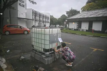 Seorang penyewa dan pemilik studio yoga di Phoenix Park, Cik Lim, sedang mengambil air daripada tangki air yang disediakan PUB untuk kegunaan di tandas. 