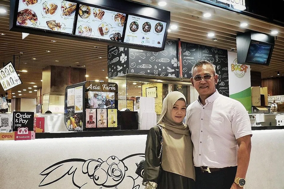 KEMBANG PERNIAGAAN: Pemilik Zoul's Corner, Encik Azhar Md Salleh (kanan), telah membuka cawangan kios pertamanya, Smash, di pusat beli-belah AMK Hub. Bersama dalam gambar ialah isterinya, Cik Maznah Baharon. - Foto BH oleh KHALID BABA