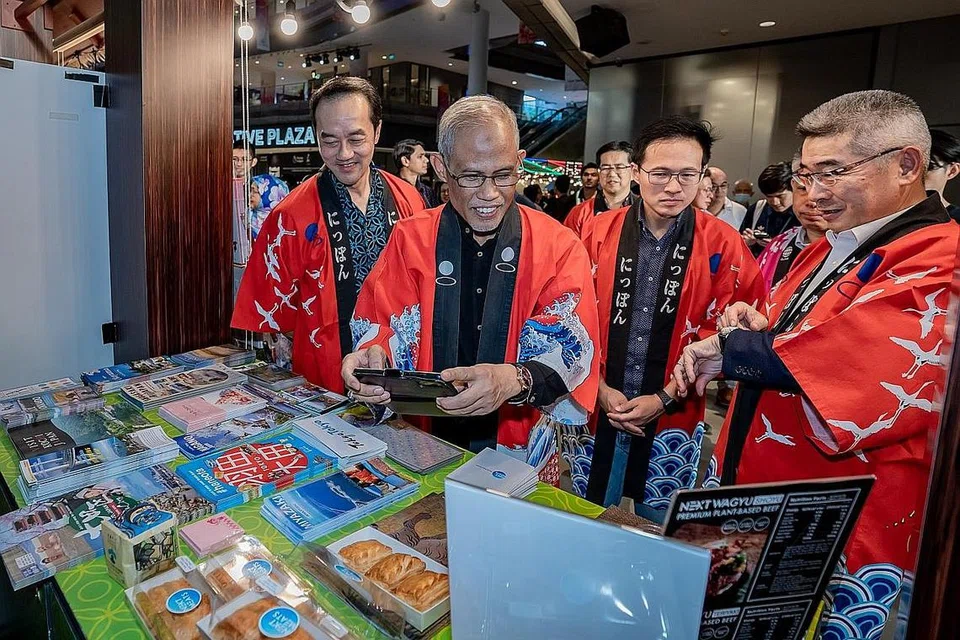 BAZAR 'INKLUSIF': Antara gerai yang tersedia di Bazar 'Retro Raya' Our Tampines Hub termasuk yang dikendalikan Kedutaan Jepun di mana produk khas Jepun diketengahkan. Penasihat akar umbi Tampines termasuk (dari kiri) Dr Koh Poh Koon, Encik Masagos Zulkifli dan Encik Desmond Choo telah mengunjungi gerai tersebut pada Sabtu. - Foto BM oleh NUR DIYANA TAHA