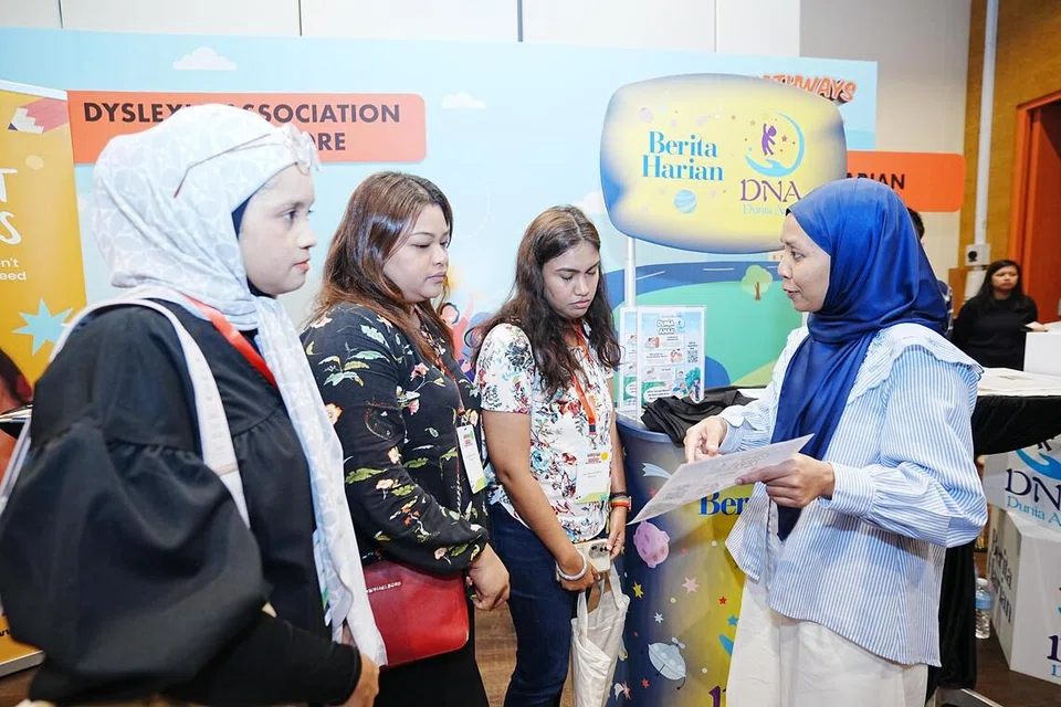 Koresponden Berita Harian (BH), Cik Nur Dhuha Esoof (kanan), yang mengendalikan ruangan DNA Dunia Anak, mendekati pembaca di reruai BH di acara Yayasan Mendaki pada November 2024.