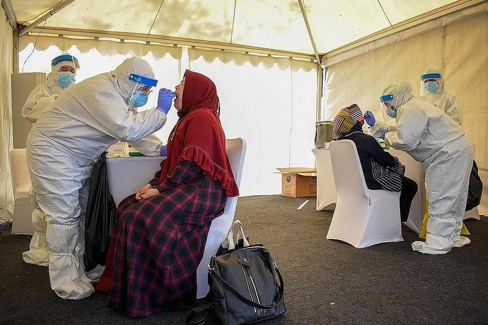 COVID-19 DI INDONESIA: (Gambar atas) Pekerja kesihatan menjalankan ujian swab ke atas orang awam di perkarangan Sekolah Pegawai Tentera di Bandung. - Foto AFP