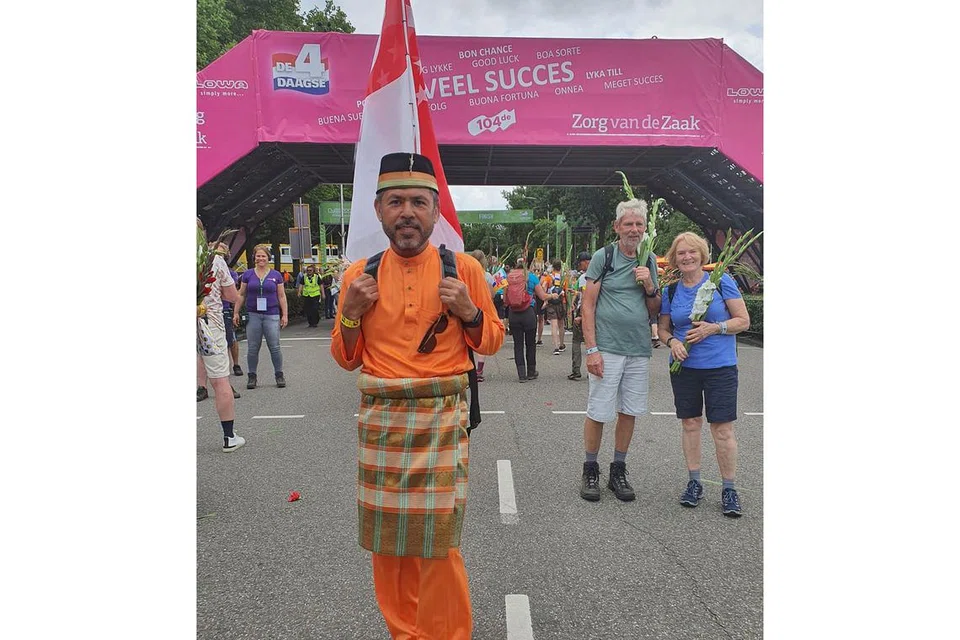 BERJALAN SAMBIL BAWA BENDERA SINGAPURA: Encik Rahmen bangga kerana berpeluang mewakili Singapura dalam acara The Walk of The World di Belanda. - Foto-foto ihsan RAHMEN ALI