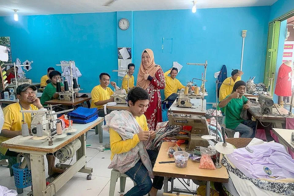 MENGUBAH STRATEGI: Pemilik Ilham Empire, Cik Nur Asyiqin Jumato (berdiri), bergambar bersama tukang jahitnya di sebuah kilang di sekitar kawasan Batam Centre, Batam, Indonesia. Beliau akan menjual bekalan pakaiannya di gerai yang disewanya di pusat beli-belah Causeway Point. - Foto-foto ILHAM EMPIRE