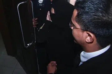 Datin Rozita Mohamad Ali (tengah) menutup mukanya daripada jurugambar di Mahkamah Sesyen Petaling Jaya selepas didakwa cuba membunuh pembantu rumah warga Indonesianya.