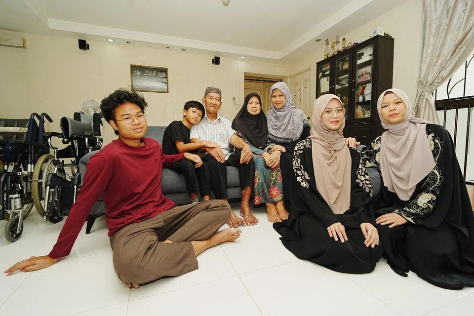 Terpaksa berhenti kerja 10 tahun lalu untuk menjaga anak lelakinya yang berkeperluan khas, keluarga Cik Hadijah Mohamed Eusope (tiga dari kanan), berdepan kesukaran untuk menyara kehidupan apabila suaminya menjadi satu-satunya pencari nafkah bagi keluarga seramai lapan orang. Setelah mendapatkan bantuan di hospital, beliau kemudian dirujuk untuk menerima sokongan daripada Masjid Al-Mawaddah sebagai penerima zakat. Hari ini, beliau merupakan antara 10,500 penerima yang meraih manfaat daripada pakej sokongan Ramadan berjumlah $4.3 juta. Bersama beliau ialah anggota keluarganya (dari kiri, barisan depan) Nur Syahindah Sanusi, Sofia Insyirah Sanusi, Muhammad Haziq Sanusi, (dari kiri, duduk di sofa) Muhammad Hariz Sanusi, Mohamed Eusope Jantan dan  Kamisah Mamat