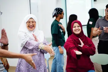 Cik Julia Ahmad, berusia 71 tahun (kiri) dan Cik Humaira Sumaiya Mohamad Fariz, berusia 24 tahun (kanan), mencuba gerakan Silat di acara “BeRiang BerKhayr” pada 23 April di Pusat Penuaan Aktif NTUC Health (Penjagaan) (Bedok North).