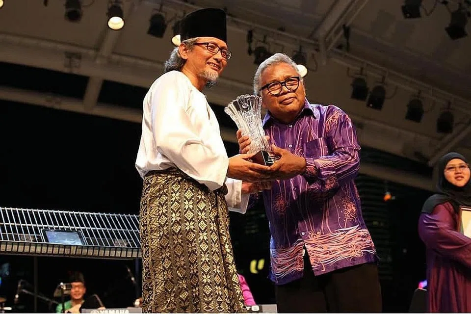 JASA DISANJUNG: Nasir Abdullah (kanan) menerima piala penghormatan daripada pengarah festival Gemadah Ariffin Abdullah atas sumbangannya memelihara seni muzik tradisional di Singapura. - Foto FACEBOOK NASIR ABDULLAH