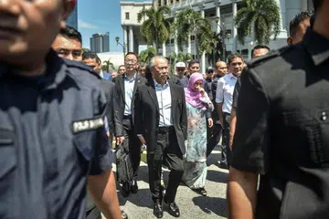 DITUDUH RASUAH: Bekas perdana menteri Malaysia, Tan Sri Muhyiddin Yassin (tengah), yang kini pengerusi pembangkang Perikatan Nasional (PN), keluar dari Mahkamah Tinggi Kuala Lumpur pada 10 Mac selepas dikenakan tuduhan rasuah, menyalah guna kuasa dan pengubahan wang haram berkaitan dana pemulihan ekonomi semasa pandemik Covid-19. 