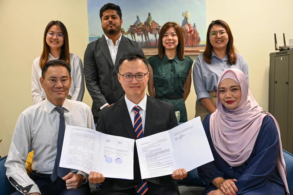 KEMBANG BERSAMA: Pengasas dan Ketua Pegawai Eksekutif (CEO) G-EMx Technologies, Encik Asmadi Ahmad, bersama kakitangan syarikatnya sambil berkongsi kedua-dua memorandum persefahaman (MOU) yang telah diraih mereka.