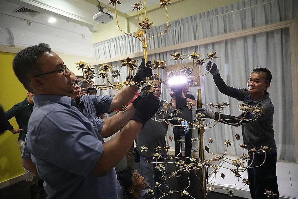 REPLIKA BUNGA EMAS: Staf kesenian mengalihkan satu replika Bunga Emas yang dipamerkan dalam pameran khas 'Seekor Singa, Seorang Putera & Sebingkai Cermin: Reflecting & Refracting Singapura' di Taman Warisan Melayu sehingga 21 Jun ini. Replika tersebut didatangkan dari Royal Mint di Bangkok dan diperbuat berdasarkan bentuk Bunga Emas asal yang diberikan kerajaan Kedah kepada Maharaja Siam (1809-1906) yang masih disimpan di Istana Besar di Bangkok. - Foto BH oleh ONG WEE JIN