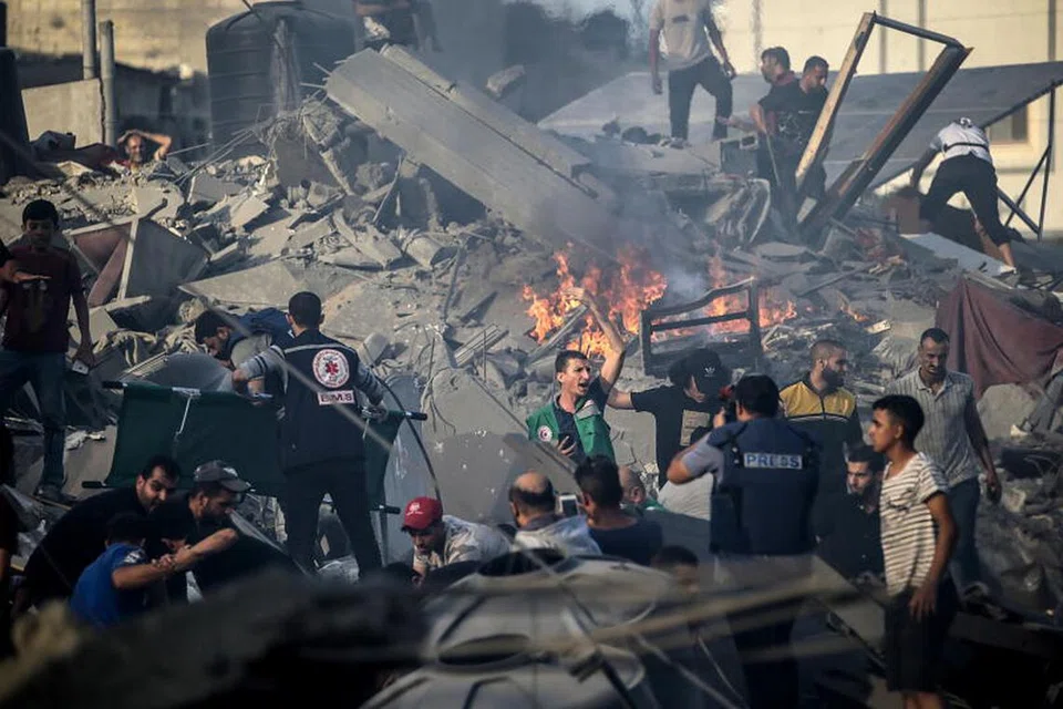 RUNTUH: Orang ramai mencari mangsa yang mungkin masih hidup di bawah bangunan yang runtuh ekoran serangan udara Israel di Gaza pada Rabu. 