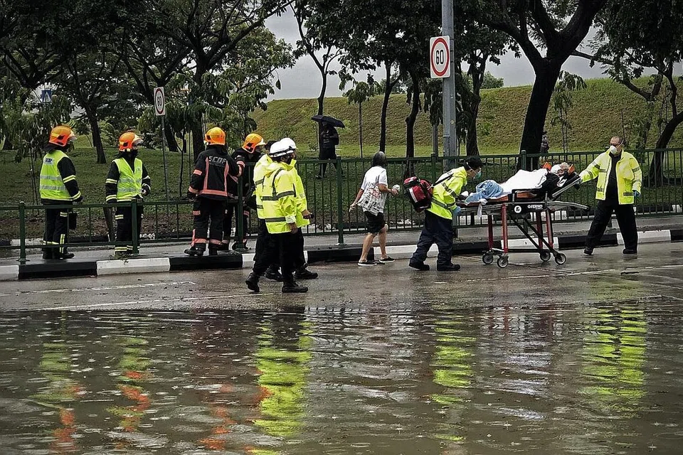 SELAMATKAN WARGA EMAS: Pegawai SCDF memindahkan seorang wanita berusia yang terperangkap dalam kenderaan akibat banjir pagi semalam. - Foto BH oleh NEO XIAOBIN