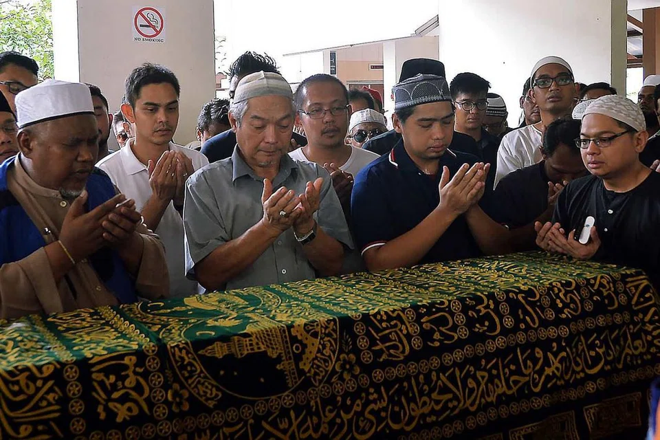HIBA ATAS PEMERGIAN ANAK: Ayah Allahyarham Nasrulhudin (depan, berbaju kelabu) sedang berdoa bersama hadirin lain di kolong blok di Tampines. - Foto-foto KHALID BABA