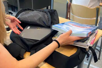 Seorang pelajar sekolah Finland menunjukkan buku dalam begnya.