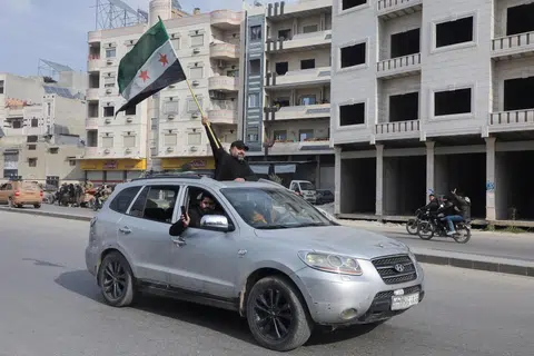 Seorang individu mengibarkan bendera pembangkang selepas pemberontak yang dipimpin oleh Hayat Tahrir al-Sham (HTS) berjaya menawan bandar utama Aleppo dan Hama, Syria, pada 6 Disember.