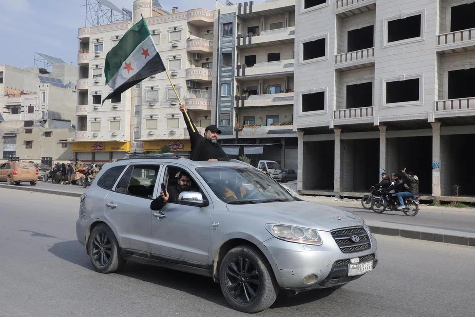 Seorang individu mengibarkan bendera pembangkang selepas pemberontak yang dipimpin oleh Hayat Tahrir al-Sham (HTS) berjaya menawan bandar utama Aleppo dan Hama, Syria, pada 6 Disember.