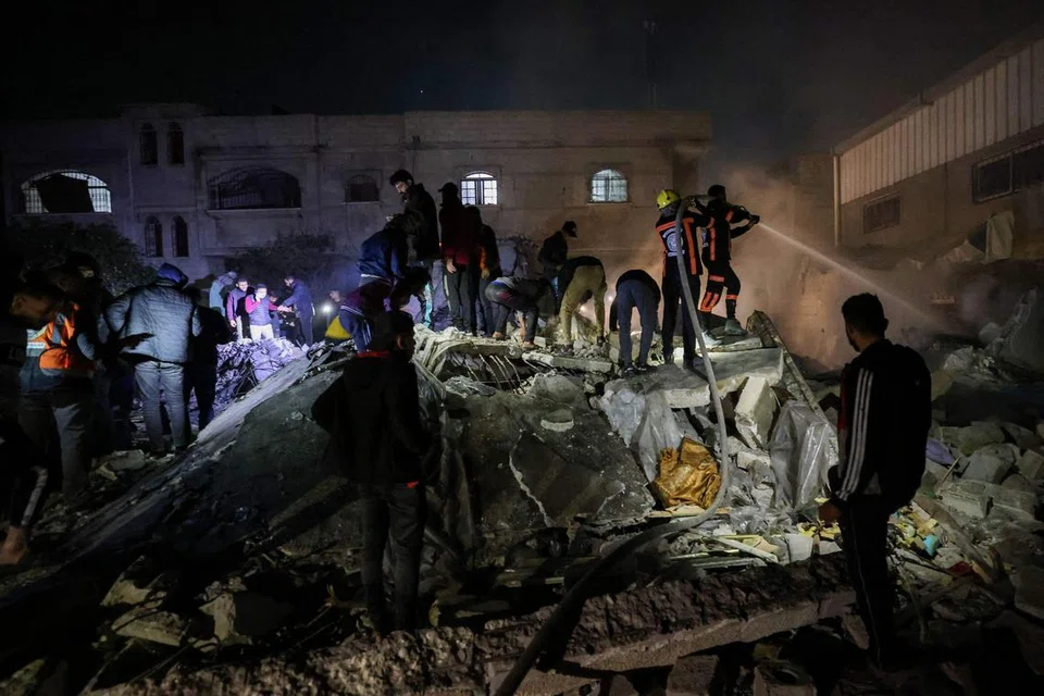 SERUAN GENCATAN SEMAKIN MENINGKAT: Para anggota bomba dan penduduk berganding bahu mencari mangsa dalam runtuhan bangunan ekoran pengeboman Israel di Rafah, selatan Gaza, pada 18 Disember.