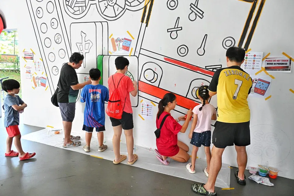 Para penduduk Fernvale mewarnakan mural di kolong blok 471B Fernvale pada pagi 20 Julai, yang menampilkan permainan tradisional seperti Congkak, Mahjong dan bola sepak takraw. 