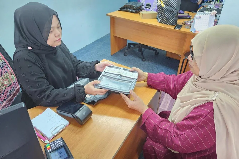 BERI SOKONGAN: Cik Waridah (kanan, baju merah pulasan) adalah jemaah pertama yang datang ke Masjid Hasanah untuk membuat pendaftaran bagi khidmat ibadah korban di luar negara yang diuruskan oleh seorang petugas daripada unit Khidmat Pelanggan (kiri, baju hitam), Cik Mukminah.