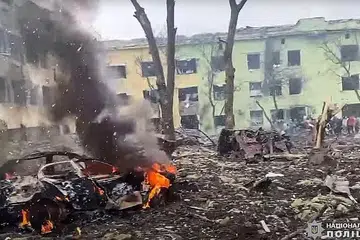 SASARAN BOM: Sebuah kereta terbakar di luar bangunan hospital kanak-kanak yang dibedil oleh tentera Russia di bandar Mariupol di tenggara Ukraine. - Foto-Foto AFP 