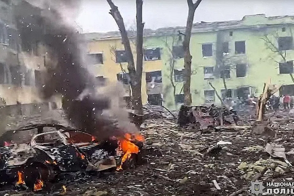 SASARAN BOM: Sebuah kereta terbakar di luar bangunan hospital kanak-kanak yang dibedil oleh tentera Russia di bandar Mariupol di tenggara Ukraine. - Foto-Foto AFP 