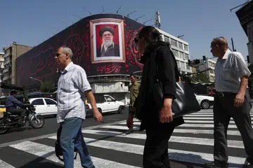 Orang ramai berjalan melepasi papan iklan yang memaparkan imej bekas Pemimpin Tertinggi Iran, Ali Khamenei, di Teheran pada 13 Julai 2026. Ketika Iran masih berkabung atas kematian pemimpin itu, negara berkenaan berdepan gelombang baharu serangan Amerika Syarikat, manakala ketegangan di Selat Hormuz terus memuncak dengan kedua-dua pihak saling mengancam di tengah usaha diplomatik yang masih buntu.