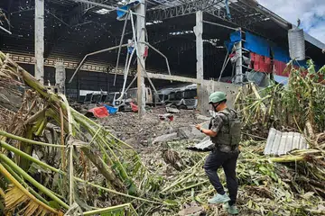 Seorang lelaki memeriksa sebuah kediaman yang rosak akibat serangan udara Thailand di bandar Poipet, wilayah Banteay Meanchey, Kemboja, susulan pertempuran di sepanjang sempadan Kemboja-Thailand pada 18 Disember.