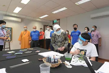 BERTEMU ARTIS ISTIMEWA: Presiden Halimah Yacob beramah-tamah bersama seorang belia berkeperluan khas, yang merupakan sebahagian program Arts@Metta, yang sedang melukis batik di Persatuan Kebajikan Metta semalam. - Foto BH oleh ALPHONSUS CHERN