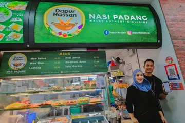 WADAH BARU: Cik Noraidah Abdul Rahim, dan suaminya pemain bola sepak negara, Encik Hassan Sunny, memanfaatkan wadah e-pembayaran bagi gerai nasi padang mereka yang dibuka Oktober tahun lalu.