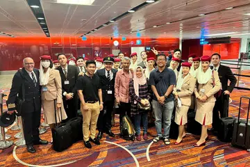 KEBANGGAAN IBU DAN AYAH: Encik Muhammad Redzuan (depan, lima dari kiri) bersama ayahnya, Encik Rashid Sulaiman (depan, lima dari kanan) dan ibunya Cik Rajiah Md Shah (depan, empat dari kanan) berserta kakitangan penerbangan A380 yang bergambar bersama di Lapangan Terbang Changi sebelum berlepas ke Dubai.
