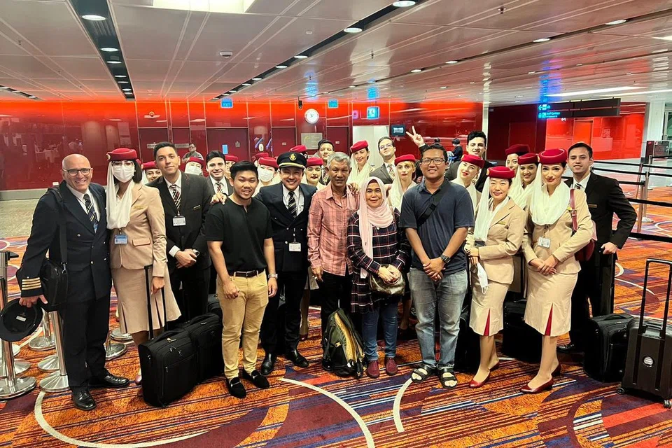 KEBANGGAAN IBU DAN AYAH: Encik Muhammad Redzuan (depan, lima dari kiri) bersama ayahnya, Encik Rashid Sulaiman (depan, lima dari kanan) dan ibunya Cik Rajiah Md Shah (depan, empat dari kanan) berserta kakitangan penerbangan A380 yang bergambar bersama di Lapangan Terbang Changi sebelum berlepas ke Dubai.