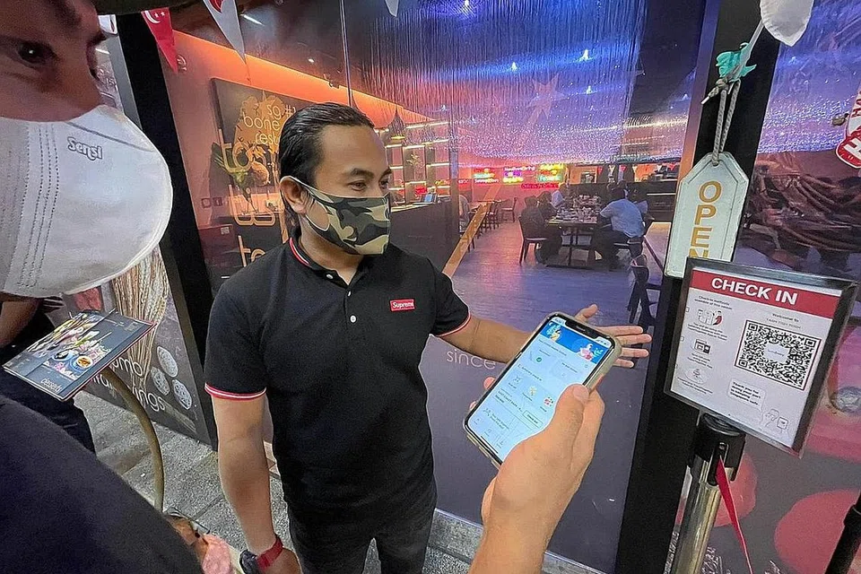 IKUT LANGKAH KESELAMATAN: Encik Azri Ariffin (kanan) periksa status vaksinasi Covid-19, SafeEntry sebelum pelanggan dibenarkan makan di restoran mereka di Marine Cove. - Foto BH oleh FAKHRURADZI ISMAIL