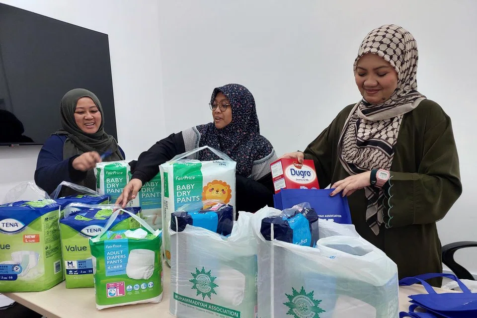 Pegawai daripada Bahagian Pendekatan dan Penglibatan Masyarakat, Persatuan Muhammadiyah, sedang membungkus lampin dan susu yang didermakan untuk diedarkan kepada benefisiari yang dikenal pasti.  