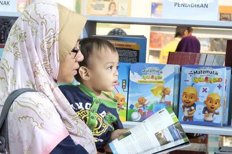TANAM TABIAT MEMBACA SEJAK KECIL: Seorang ibu meninjau buku sesuai buat anak-anak dalam Pesta Buku Antarabangsa Kuala Lumpur (PBAKL) di Pusat Dagangan Dunia Putra (PWTC), Jalan Tun Ismail, Wilayah Persekutuan Kuala Lumpur, lewat April lalu. - Foto-foto NURUL AIN RAZALI
