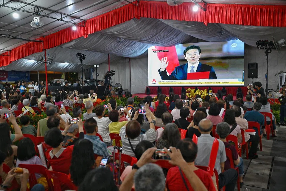 Orang ramai berkumpul di kawasan lapang bersebelahan stesen MRT Yew Tee untuk menyaksikan upacara angkat sumpah Encik Lawrence Wong sebagai Perdana Menteri baru negara pada 15 Mei.
