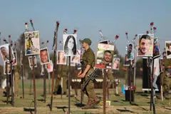 MEMORIAL: Askar Israel melihat gambar mangsa festival muzik Nova di tapak festival berhampiran Kibbutz Reim, berhampiran sempadan Gaza di selatan Israel, pada 29 November. Lebih 360 orang yang menghadiri festival itu terbunuh semasa serangan  Hamas pada 7 Oktober. 