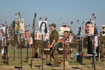 MEMORIAL: Askar Israel melihat gambar mangsa festival muzik Nova di tapak festival berhampiran Kibbutz Reim, berhampiran sempadan Gaza di selatan Israel, pada 29 November. Lebih 360 orang yang menghadiri festival itu terbunuh semasa serangan  Hamas pada 7 Oktober. 