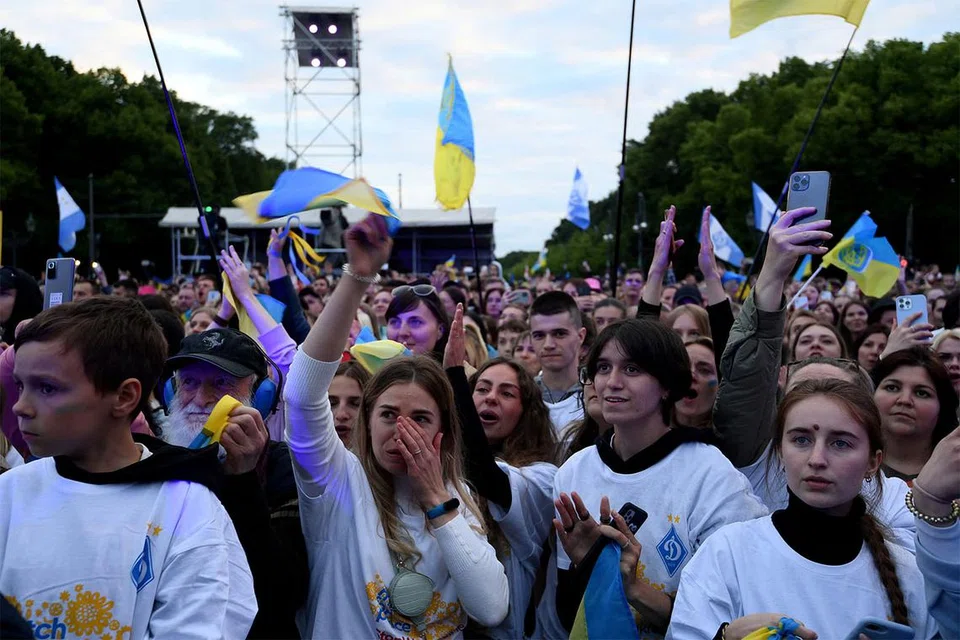 HIMPUNAN BANTAH PEPERANGAN: Orang ramai mengibarkan bendera Ukraine di depan Brandenburg Gate di Berlin, Jerman, kelmarin ketika menghadiri acara amal 'Save Ukraine - #StopWar' bagi menyokong Ukraine di tengah-tengah pencerobohan Russia ke atas negara itu. - Foto REUTERS
