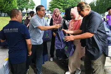 AGIH DAGING KORBAN: Sukarelawan menerima daging korban  daripada Dr Muhammad Faishal Ibrahim (dua dari kiri) untuk mengagihnya kepada benefisiari di bawah Rangkaian Pemulihan MMO.