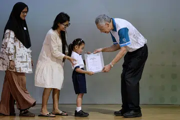 Antara yang menerima biasiswa daripada Encik Lee Hsien Loong ialah (dua dari kanan) adik Mikayla Aulani, 8 tahun yang menerima Biasiswa Merit Edusave, sambil ditemani oleh (dari kiri) neneknya, Cik Sarimah Mohd serta ibunya, Cik Baihirah Nurul Baihirah Hanim. 