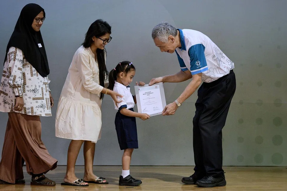 Antara yang menerima biasiswa daripada Encik Lee Hsien Loong ialah (dua dari kanan) adik Mikayla Aulani, 8 tahun yang menerima Biasiswa Merit Edusave, sambil ditemani oleh (dari kiri) neneknya, Cik Sarimah Mohd serta ibunya, Cik Baihirah Nurul Baihirah Hanim. 