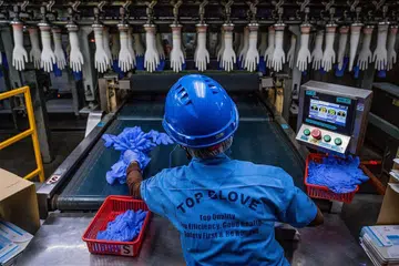 PEKERJA DIJANGKITI: Sehingga kelmarin, 1,889 kes Covid-19 direkod dalam kalangan pekerja kilang Top Glove, pengeluar sarung tangan getah terbesar di dunia. - Foto AFP