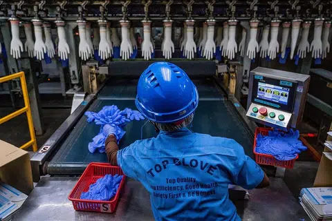 PEKERJA DIJANGKITI: Sehingga kelmarin, 1,889 kes Covid-19 direkod dalam kalangan pekerja kilang Top Glove, pengeluar sarung tangan getah terbesar di dunia. - Foto AFP