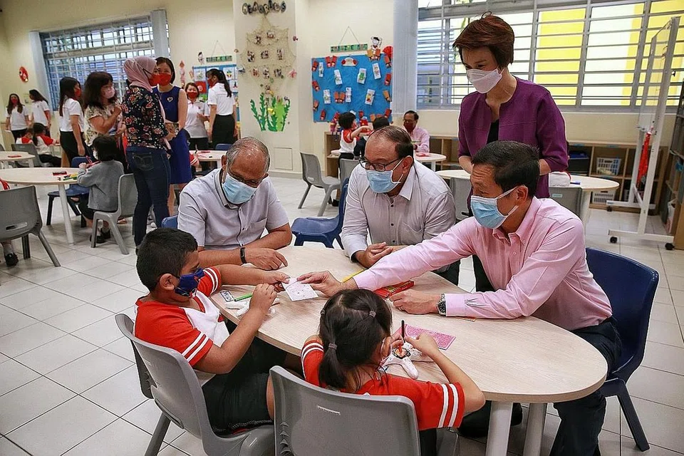 TAWAR BANTUAN: (Dari kiri) Encik Masagos Zulkifli, Encik S Iswaran, pengerusi SHGL Cik Low Yen Ling (berdiri), dan Encik Ong Ye Kung dilihat sedang menemui beberapa pelajar darjah satu ketika pembukaan Pusat Jagaaan Pelajar Big Heart yang ke-30 di Sekolah Rendah Zhangde. - Foto BH oleh KEVIN LIM