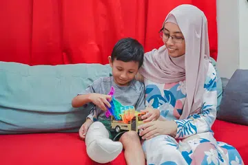 HIDUP DITERUSKAN: Cik Juliana Jomiri dan anaknya, Imraan Danish Nur Hisyam, tetap ceria meskipun anaknya itu baru melalui pembedahan bagi memotong  bahagian kanan kakinya, di bawah lutut. 