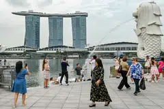 Pengunjung bergambar di patung Merlion berdekatan Marina Bay Sands pada Disember.